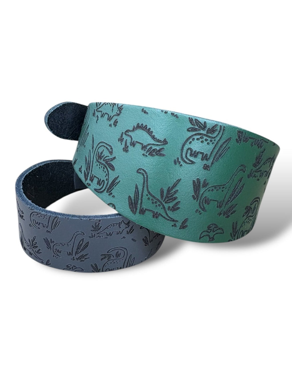Two fabric straps with dinosaur pattern on a white background