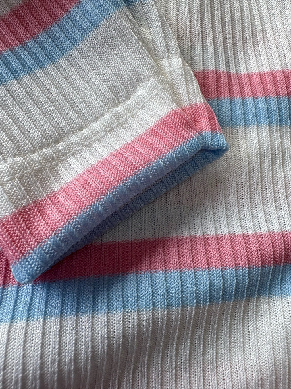 Close-up of a striped fabric with blue, pink, and white colors.