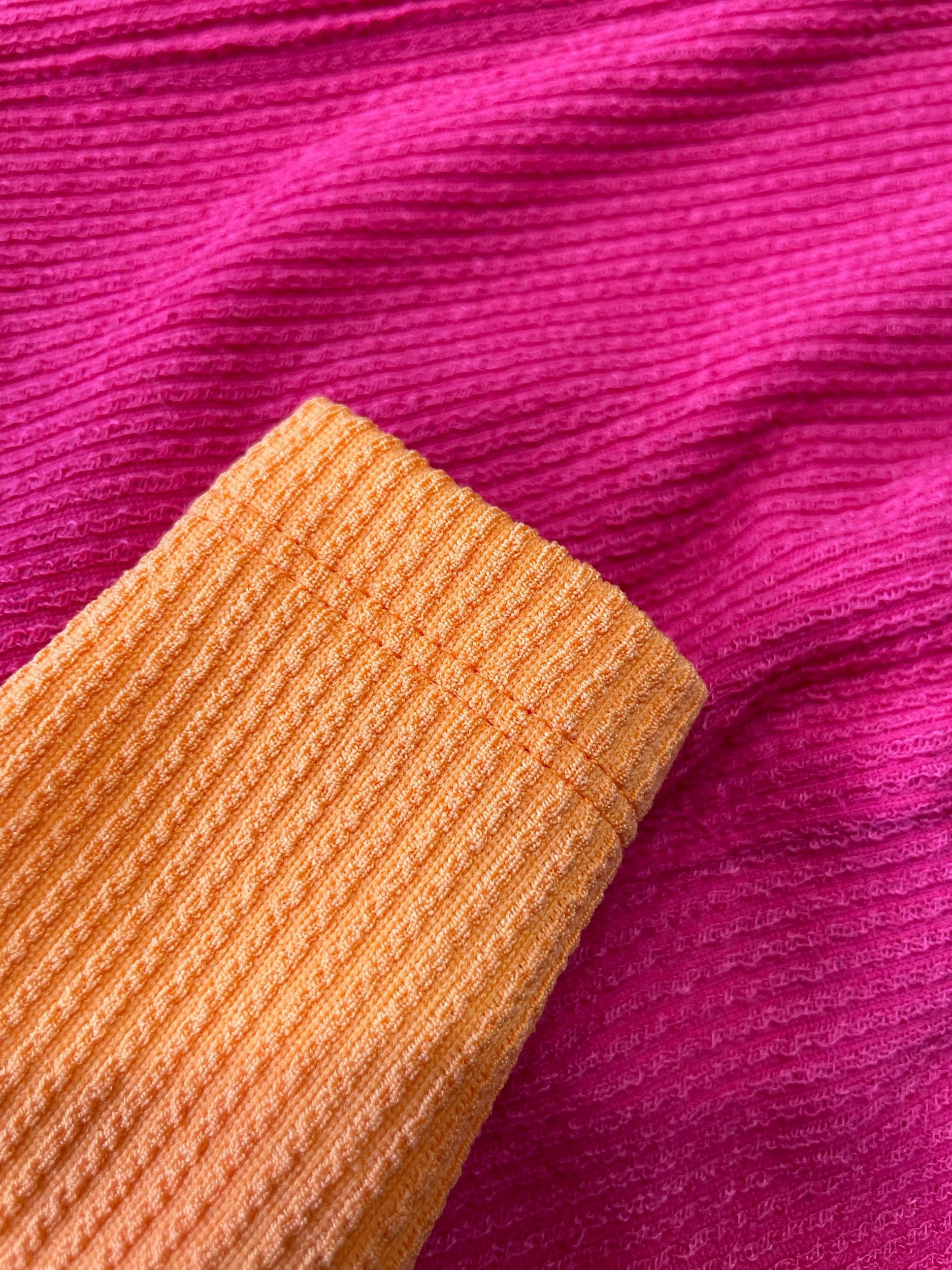Close-up of pink fabric with a textured orange strip