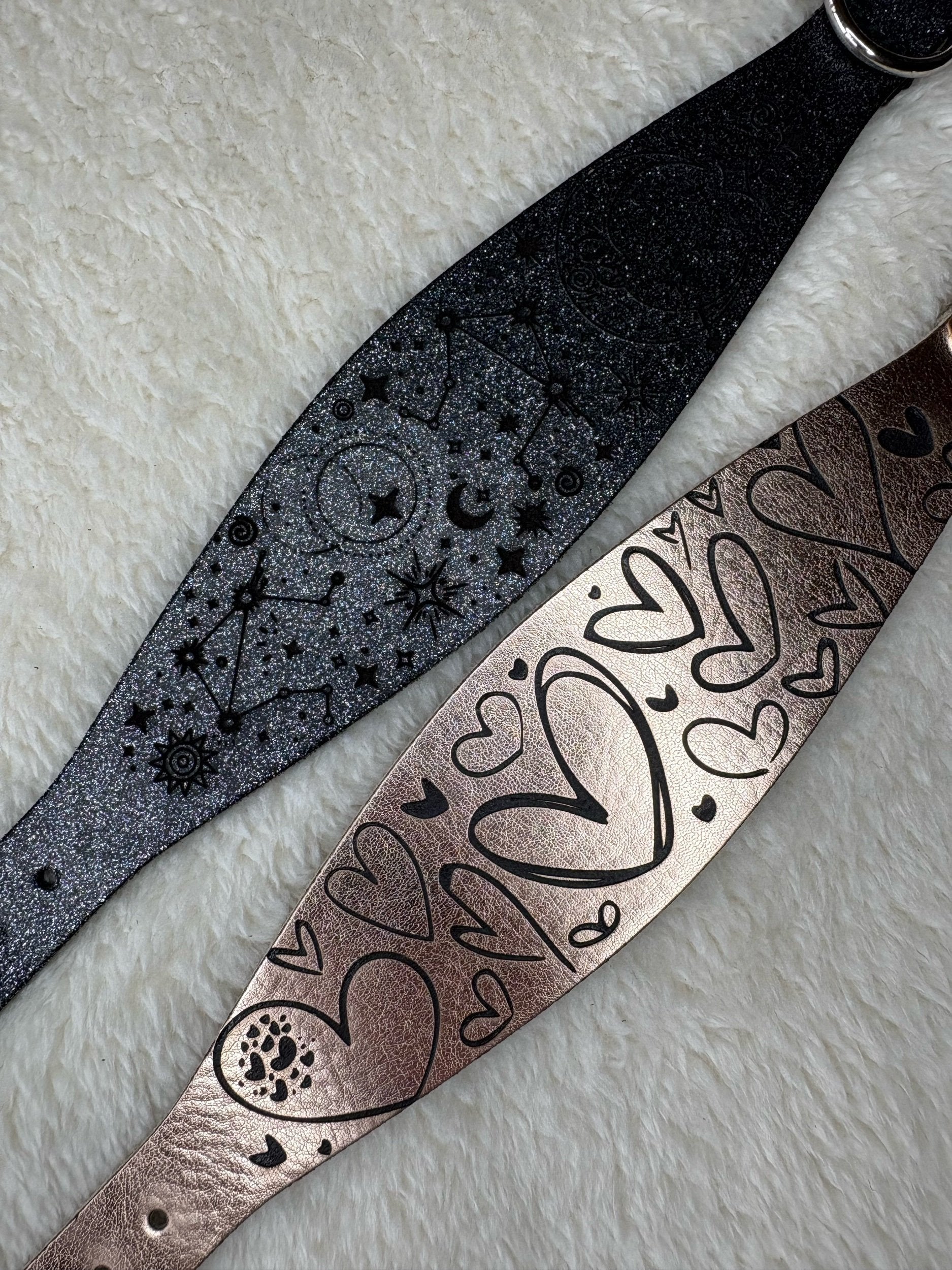 Two leather straps with embossed designs on a textured surface