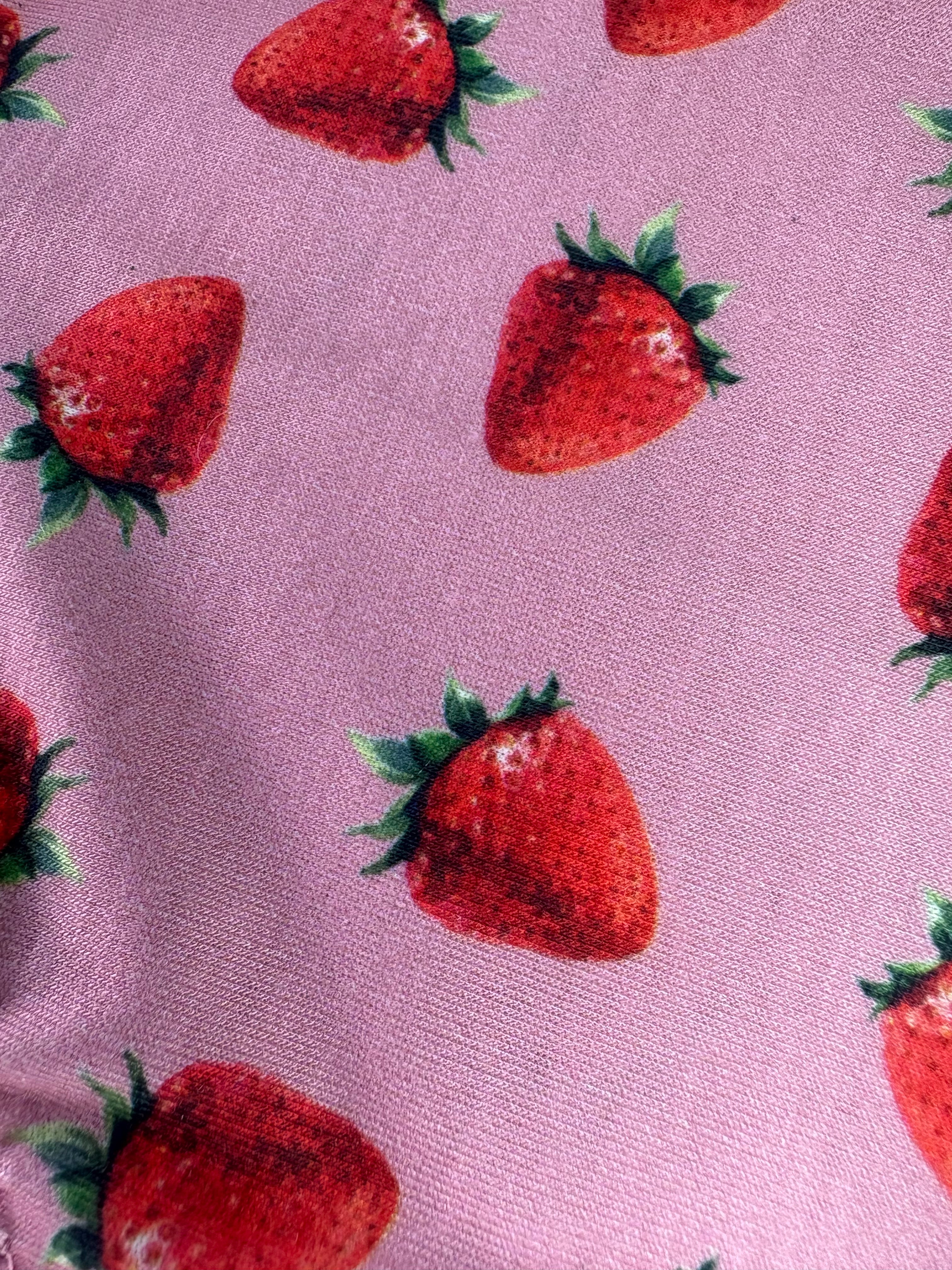 Red strawberries with green leaves on a pink fabric background