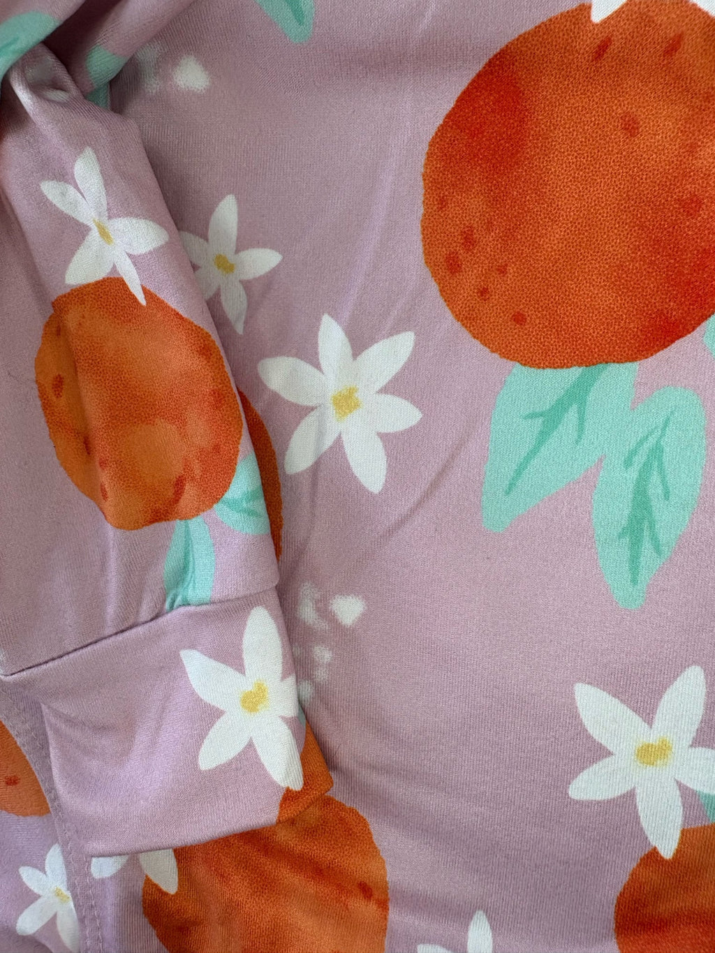 Close-up of a fabric with orange and flower pattern on a pink background
