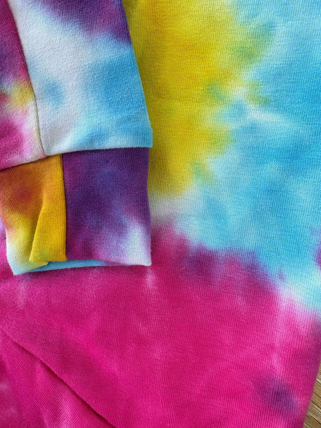 Close-up of tie-dye fabric with vibrant colors including pink, yellow, blue, and orange.