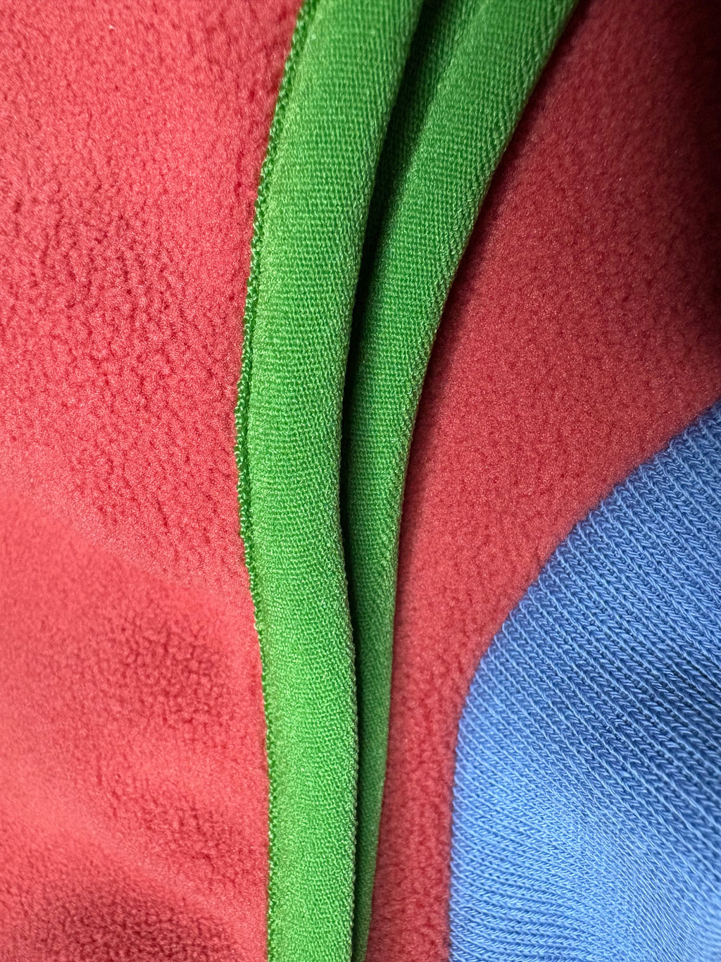 Close-up of a green zipper on a red and blue fabric background