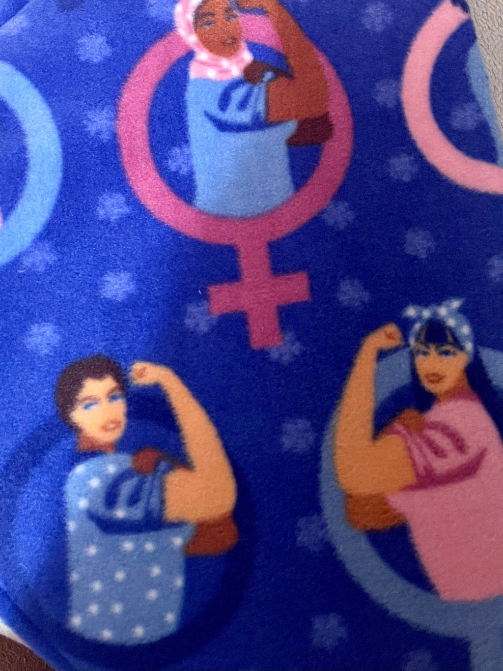 Patterned fabric with female gender symbols and illustrated women on a blue background.