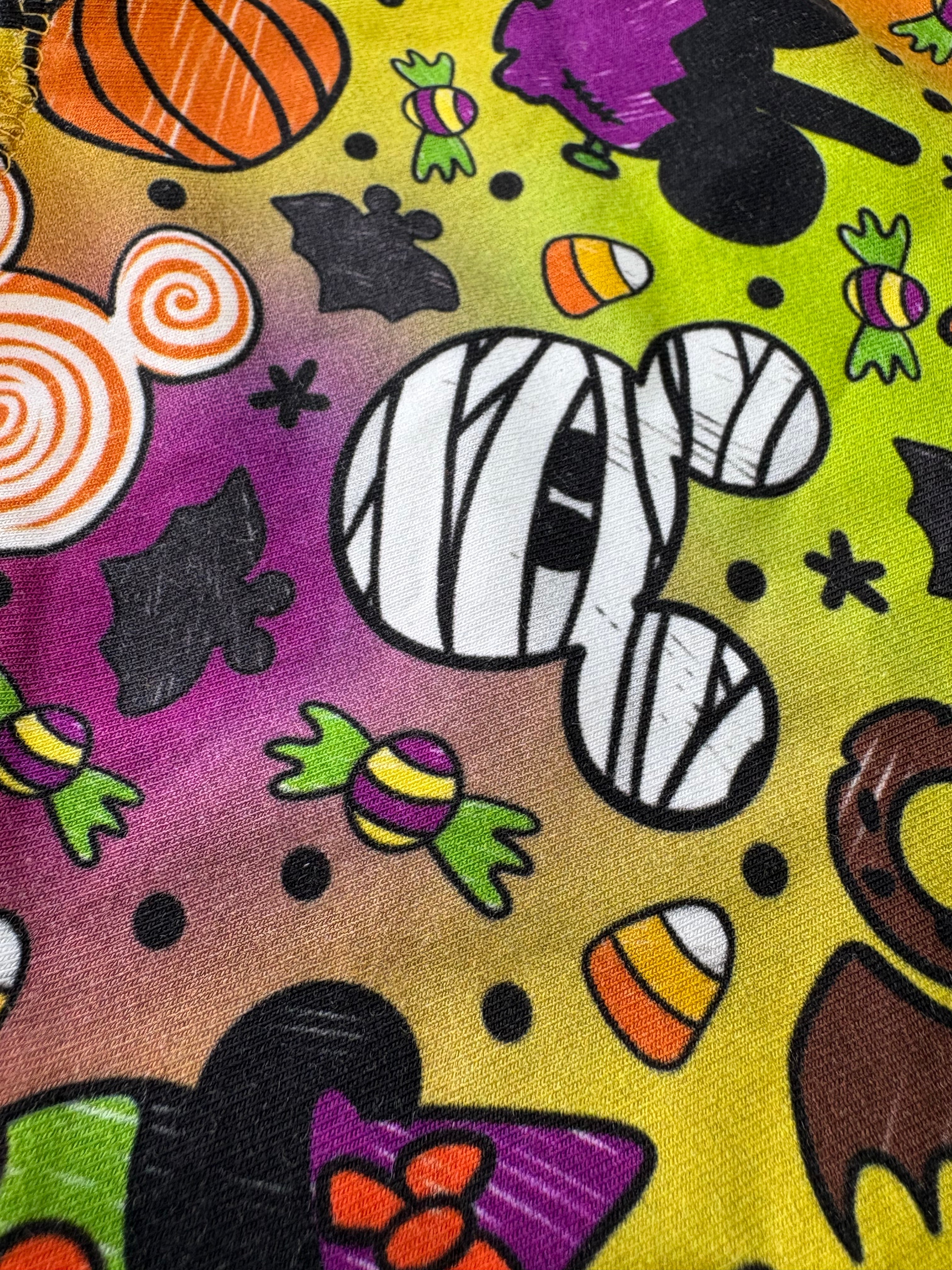 Colorful Halloween-themed fabric with mummies, pumpkins, and candy patterns.