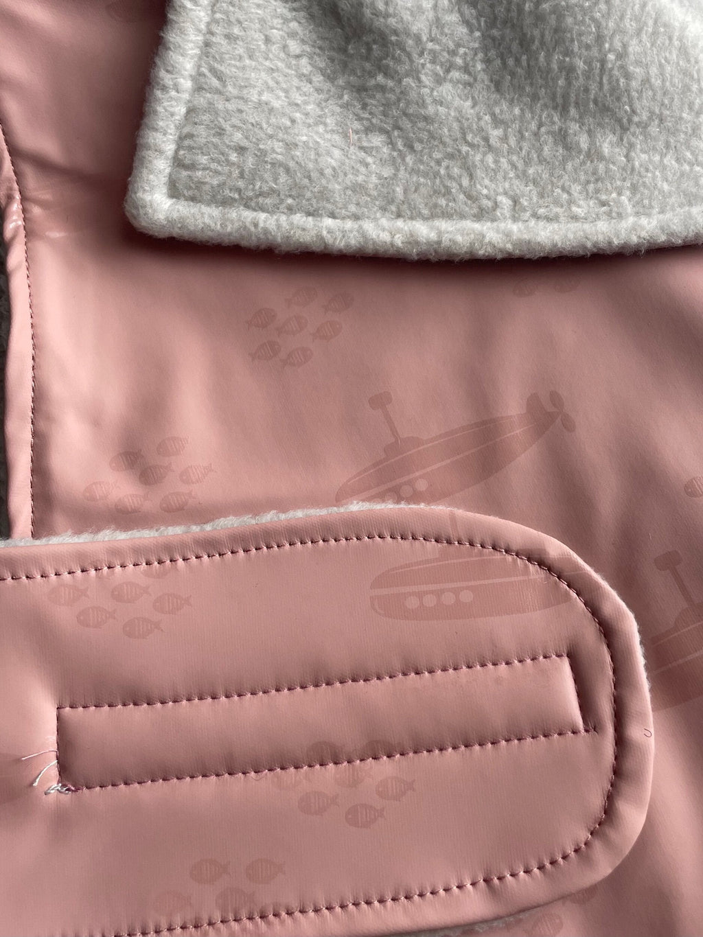 Close-up of a pink textured surface with a gray fabric layer above it.