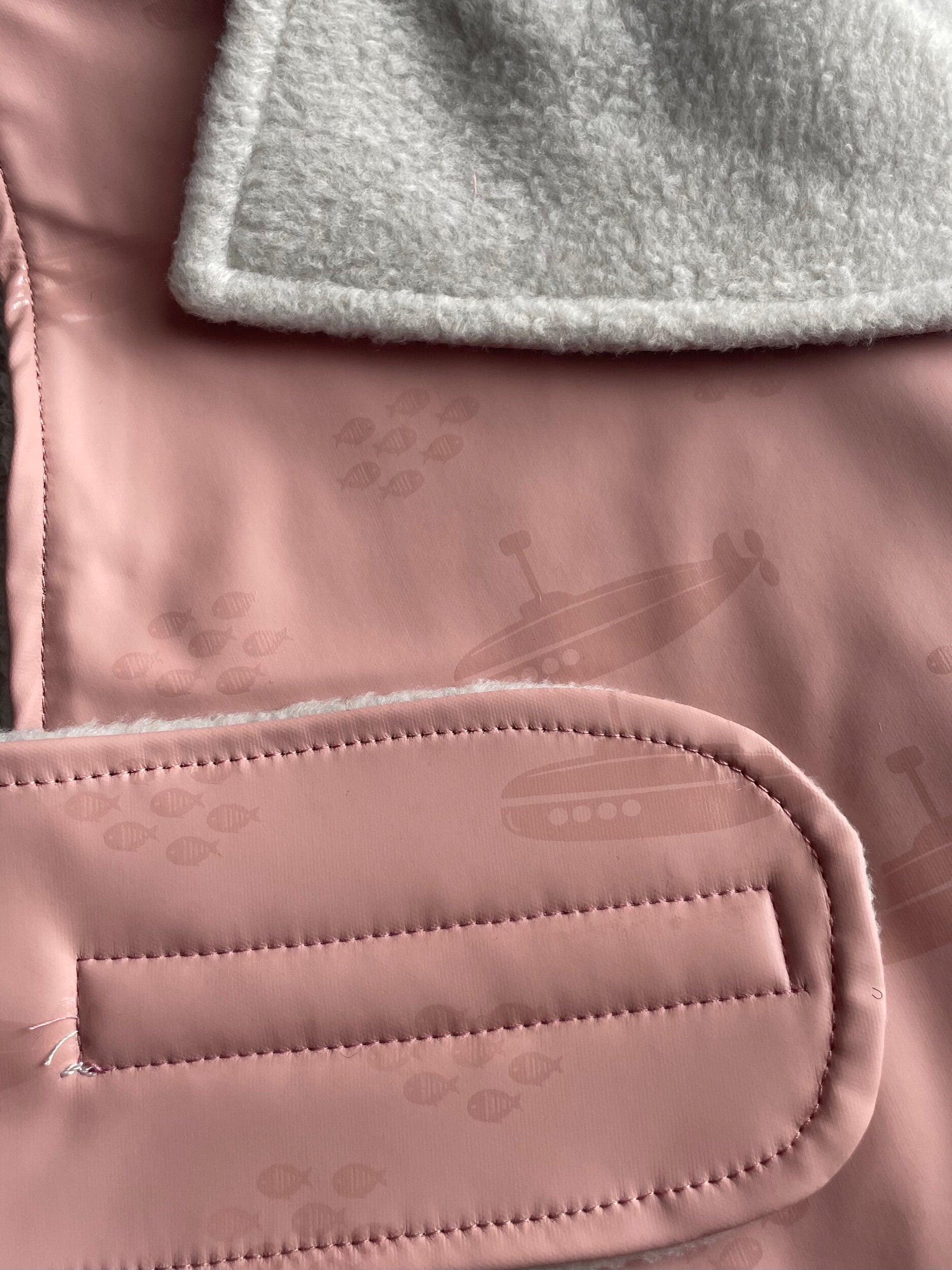 Close-up of a pink textured surface with a gray fabric layer above it.