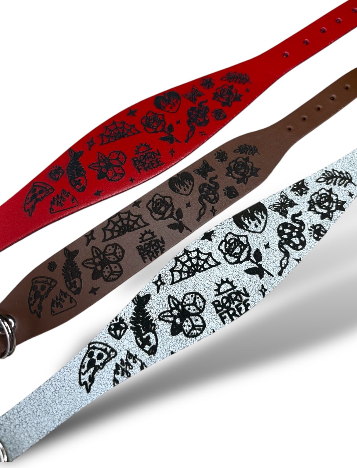 Three guitar straps with black floral patterns on red, brown, and light blue backgrounds.