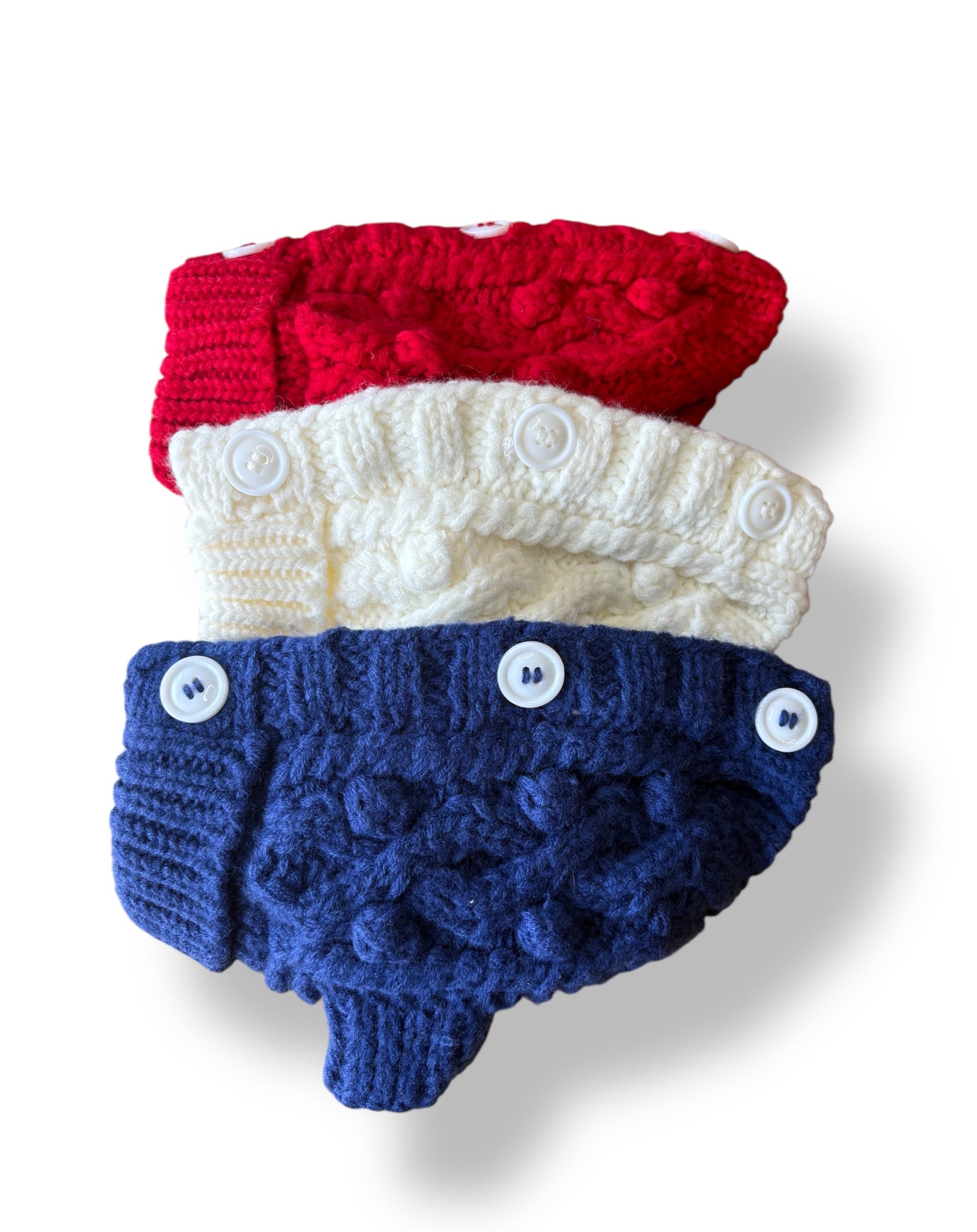 Stack of red, white, and blue knitted baby booties on a white background