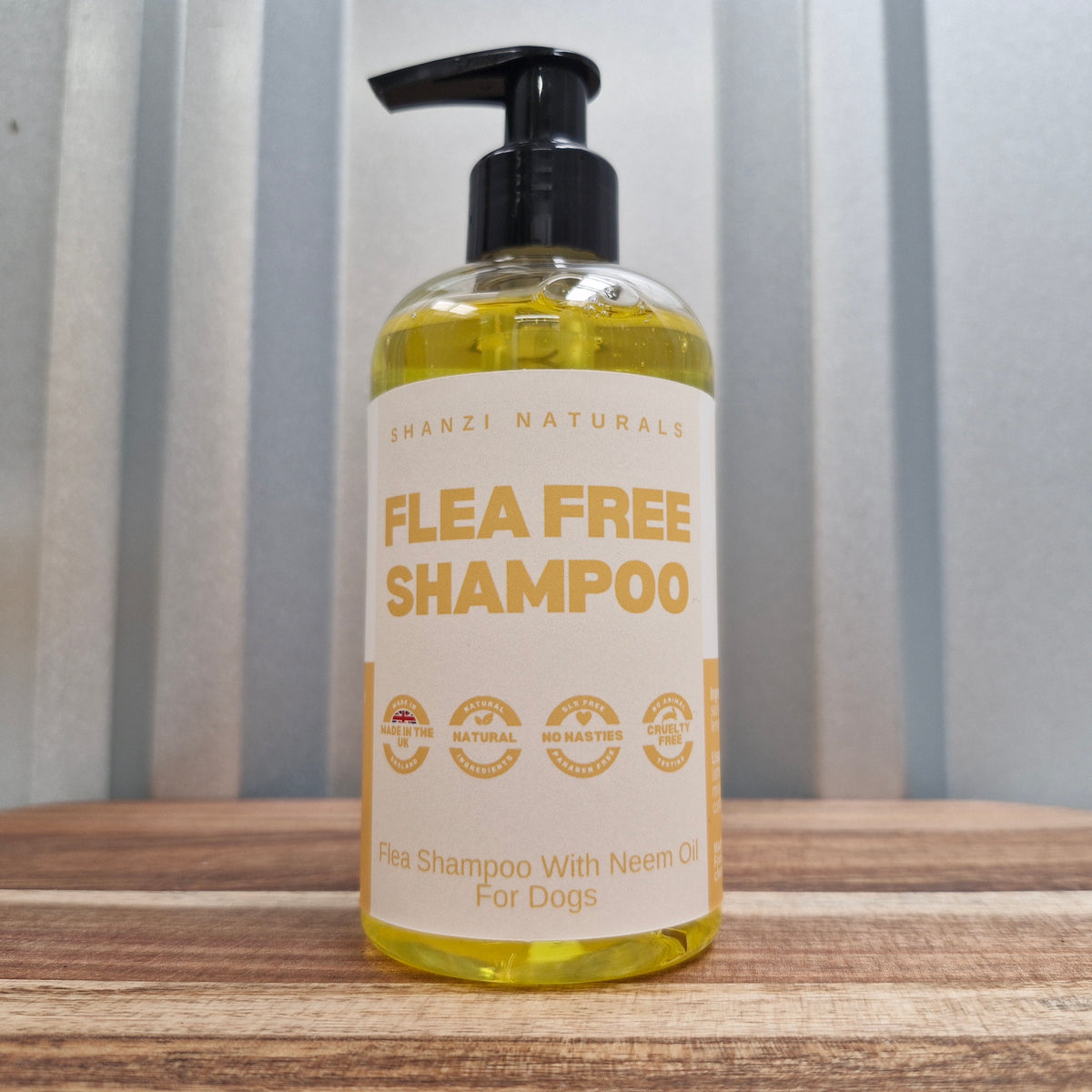 Bottle of Shanzi Naturals flea free shampoo for dogs on a wooden surface with a striped background