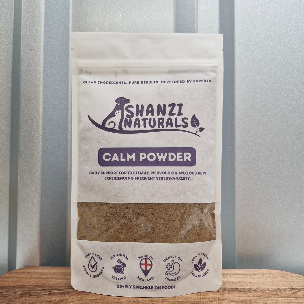 Shanzi Naturals Calm Powder packaging on a wooden surface with a striped background