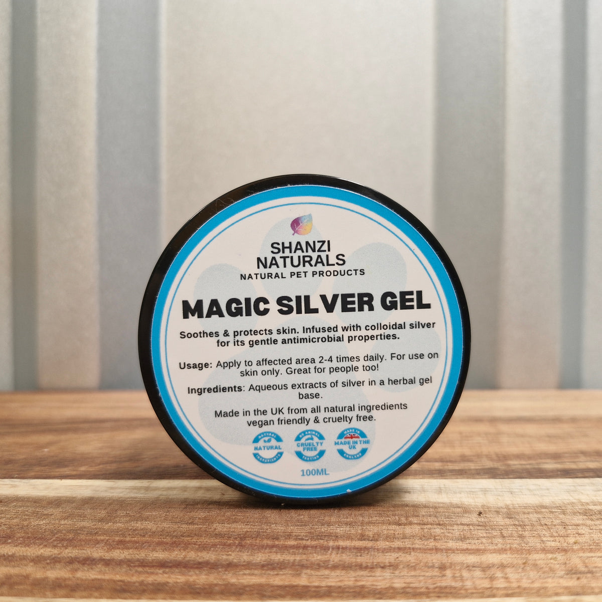 Shanzi Naturals Magic Silver Gel container on a wooden surface with a striped background